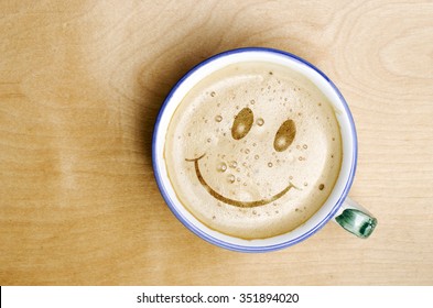 Foam Form Of Smile Face In Cup Of Cappuccino Coffee On Wooden Table.