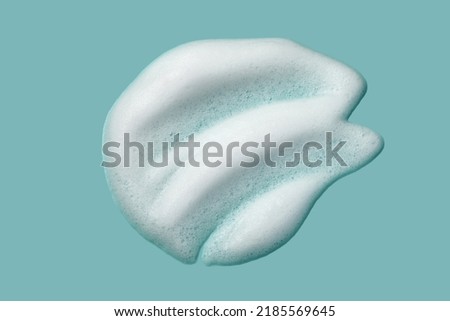 Foam lather texture background. White cleanser gel, shaving foam, shampoo bubbles on blue.