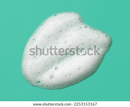 Foam lather texture background. White cleanser gel, shaving foam, shampoo bubbles on mint green color