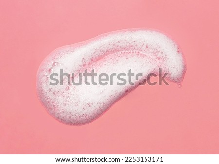 Foam lather texture background. White cleanser gel, shaving foam, shampoo bubbles on pink