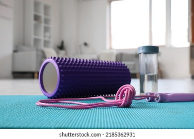 Foam Roller With Skipping Rope And Bottle Of Water On Mat In Living Room