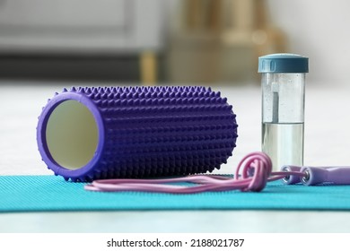 Foam Roller With Skipping Rope And Bottle Of Water On Mat In Living Room