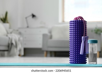 Foam Roller With Skipping Rope And Bottle Of Water On Mat In Living Room