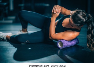 Foam Roller. Sportswoman Using Foam Roller Massager to Stretch Muscles
