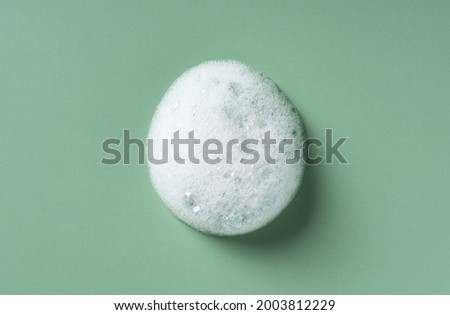 Foam texture on green background. Soap, shampoo, mousse, shower gel foam.