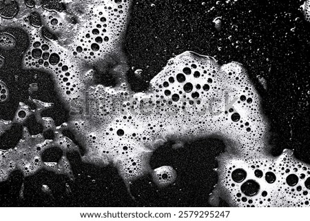 Foam texture. White bubbles on a black background. Washing a frying pan. Soapy texture. Cleaning process backdrop. Smudges of water with detergent.