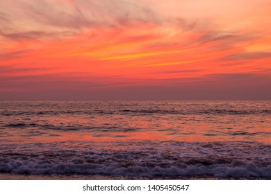 foam of the waves of the sea against the backdrop of bright purple and orange sunset sky