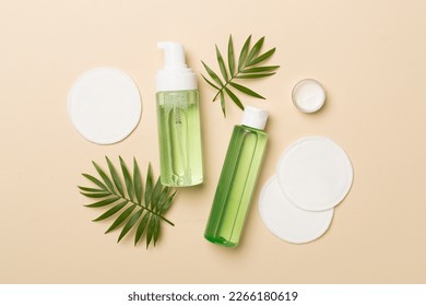 Foaming facial cleanser and micellar water with eco pads on color background, top view - Shutterstock ID 2266180619