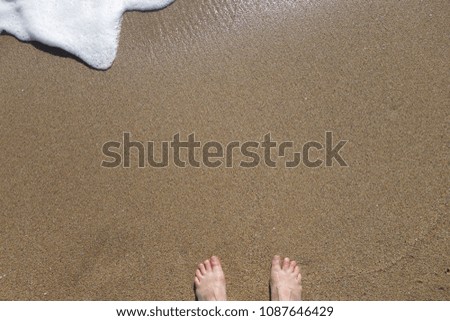 foaming white seawater on the beach with feets