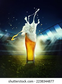 Foamy splashes. Mug with lager chill beer on grass at football stadium over evening sky with flashlights. Concept of sport, festival, competition, alcohol drinks, match. Copy space for ad.