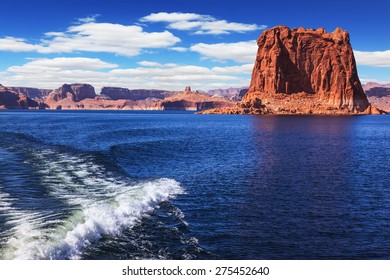  Foamy trace of a motor boat crosses the emerald waters. In the distance the coast of red sandstone. Lake Powell on the Colorado River