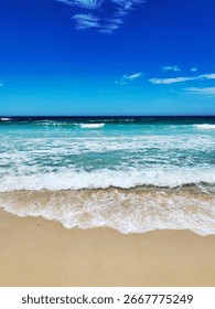 Foamy Turquoise Ocean Waves Rolling onto Sandy Shore under Bright Summer Sky