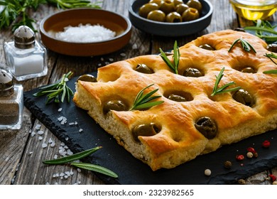 Focaccia alle olive - baked sandwich with green olives and rosemary on wooden background  - Powered by Shutterstock