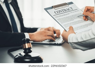 Focus contract paper on blur background of legal team or lawyer colleagues drafting legal documents in law firm office. Ethical and lawful resolution for clients disputes. Equilibrium
