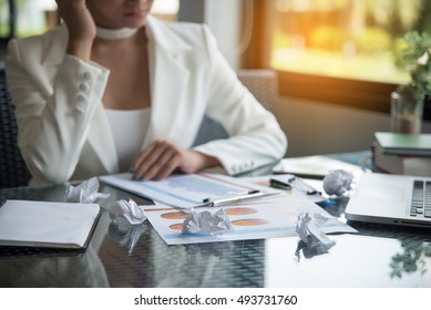 Focus At Crumpled Paper,Laptop,report And Notebook On Office Desk.Young Business Woman Stressed Jobs,headaches And Worry With Bad Coworker .Working Asian Woman Wearing White Suit ,sitting At Office.