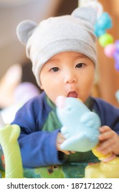 Focus In The Eyes Of Asian Infant Baby Wearing Beanie Hat And Playing Toy By Bring It To The Mouth