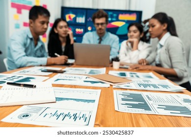 Focus financial data dashboard paperwork and blurred group of business people or analyst team analyzing business investment opportunity and perform research, data analysis and market trend. Meticulous - Powered by Shutterstock