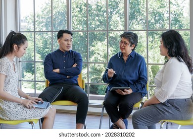 Focus Group Of Mental Health By Psychologist Consultant. Asian People Meeting Together To Talk Problem And Receive Mental Treatment. Senior Doctor Leader Speaking To Diversity Man And Woman Patients.