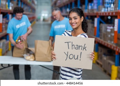 Focus of happy volunteer posing and holding a sign in a warehouse - Powered by Shutterstock