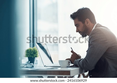 Focus and intention will get you far. Shot of a handsome young businessman using a laptop and cellphone at his desk in a modern office.