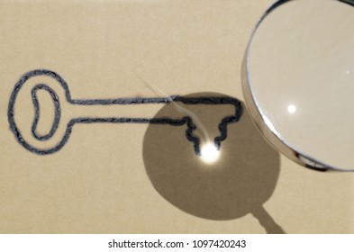 Focus is key (one key version), illustrated by using magnifying glass to focus sunlight to create key shaped burn mark on piece of brown paper