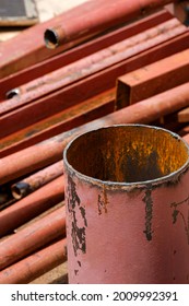 Focus At The Old Brown Carbon Steel Pipe With Blurred Heap Of Various Steel Tube Material On The Floor In Construction Site