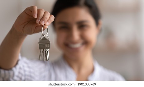 Focus On Bunch Of Keys From House Flat Apartment In Hand Of Smiling Female. Blurred Portrait Of Confident Woman Professional Realtor Offering New Dwelling Real Estate Unit To Potential Buyer. Close Up