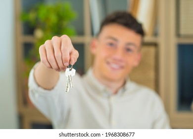 Focus On Bunch Of Keys From House Flat Apartment In Hand Of Smiling Teenager. Blurred Portrait Of Confident Man Professional Realtor Offering New Dwelling Real Estate Unit To Potential Buyer. Close Up