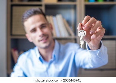 Focus on bunch of keys from house flat apartment in hand of smiling male. Blurred portrait of confident man professional realtor offering new dwelling real estate unit to potential buyer. Close up - Powered by Shutterstock