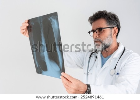 Focus on chest X-ray examination studied by multiracial healthcare practitioner. Male radiologist identifying mass in left lung using technologies.