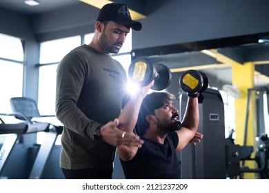 Focus On Client, Gym Trainer Helping Athlete To Use Dumbells During Workout - Concept Of Fitness Training, Personal Coach And Bodybuilding.