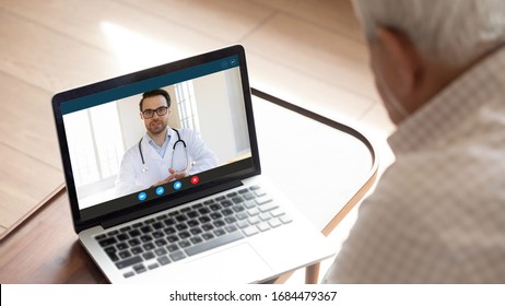 Focus on computer screen with confident happy male family doctor general practitioner consulting giving advices to older mature worried man patient with sickness symptoms online via video call.