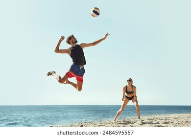 Focus on concentrated young man, player in motion, hitting ball in a jump. Young people, friends playing each volleyball be the sea. Concept of sport, summer, nature, active lifestyle, youth - Powered by Shutterstock