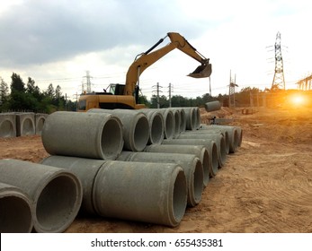 Focus on concrete pipes and backhoe to construct drainage systems on large power plant projects.Cement drainage pipes for industrial building construction,selective focus. 