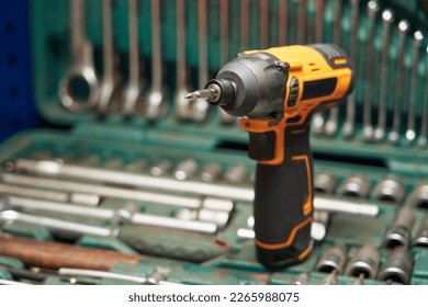 focus on cross bat. a beautiful bright cordless electric screwdriver with a cross bit stands on a case with a tool, with open-end wrenches, bits, heads