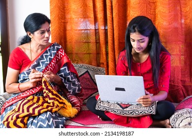 focus on daughter, mother busy stitching while daughter working on laptop - concept of conversation, parental care and togetherness