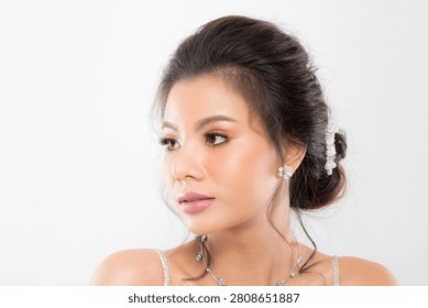 Focus on the delicate features of an elegant bride sparkling earring necklace and a gentle touch emphasizing her sophisticated allure studio shot on white background.