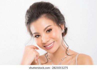 Focus on the delicate features of an elegant bride sparkling earring necklace and a gentle touch emphasizing her sophisticated allure studio shot on white background.