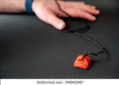 Focus on exercise equipment emergency stop laying on a treadmill belt with a Caucasian hand in the background