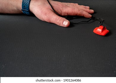 Focus on exercise equipment emergency stop laying on a treadmill belt with a Caucasian hand in the background