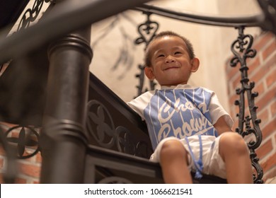 Focus On A Face Of Adorable Little Boy Who Look Very Happiness.  Portrait Of Young Toddler Who Sitting On Metal Stair