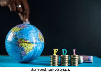 Focus on FDI letters on coins, Concept of FDI or foreign direct investment, Showing by placing coins inside the globe from behind