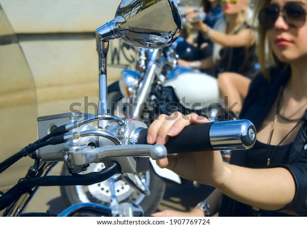 Focus on
finger.Three Young girls sitting on chopper bike and wear black
leather dress and stylish sunglasses. 3 Biker Woman on motorcycle
on green grass medow background. season
opening
