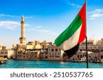 Focus on a flag of   United Arab Emirates flag against  bay Creek and Grand Bur Dubai Masjid Mosque in Dubai, United Arab Emirates