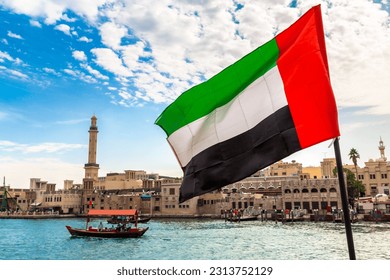Focus on a flag of  United Arab Emirates flag against Abra - old traditional wooden boat and Grand Bur Dubai Masjid Mosque on the bay Creek in Dubai - Shutterstock ID 2313752129