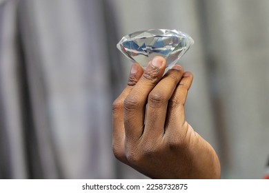 Focus on foreground of fingers holding a diamond. - Shutterstock ID 2258732875