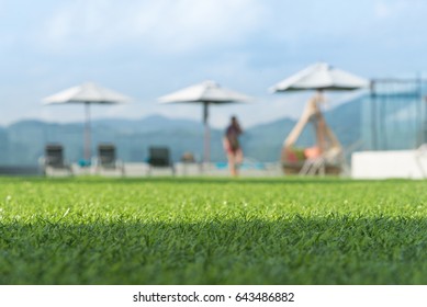 focus on front of artificial grass floor  with  people and sunbed blurred background