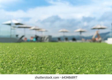 focus on front of artificial grass floor  with  sunbed blurred background