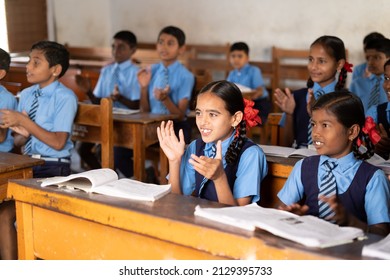 Focus on girl, young school kids in uniform applauding or clapping at classroom - concept of growth, entertainment, inspiration and childhood lifestyle. - Shutterstock ID 2129395733