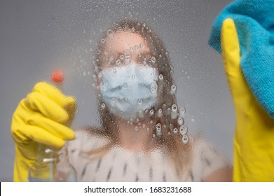 Focus on glass. Cleaning with viruses and bacteria at home. The girl in the mask cleans with a chemical agent in the mask and gloves. The problem with the purity of the coronavirus